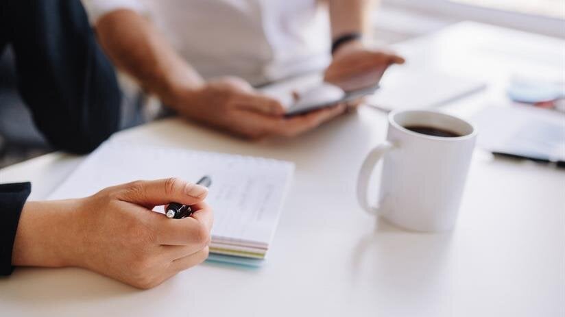 A person holding a pen and writing on a notebook