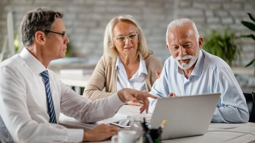 A financial advisor shows retirement options to a senior couple in a modern office.