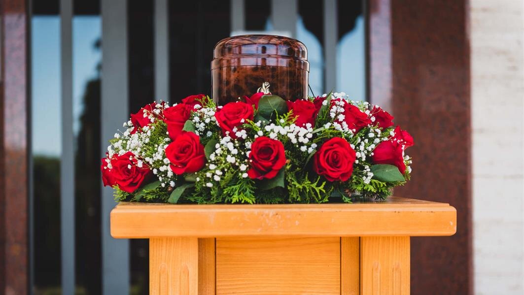 A beautiful display of red roses and an urn honoring someone's memory at a memorial.