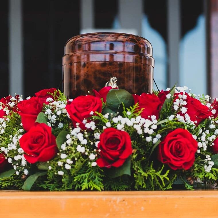 A beautiful display of red roses and an urn honoring someone's memory at a memorial.