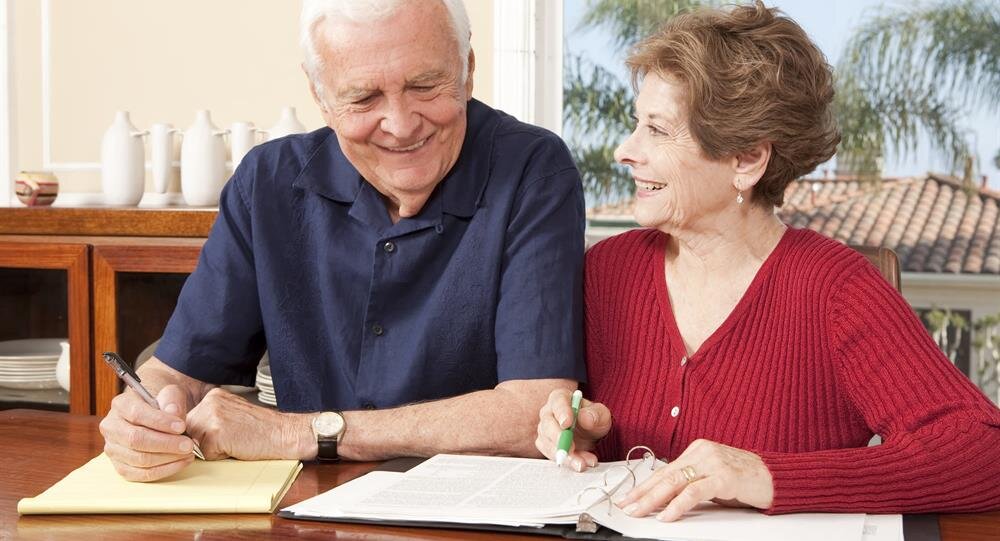 Golden sunlight filters through trees in an autumn park, highlighting vibrant leaves on the ground.