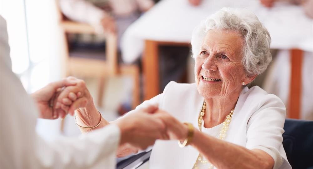 Golden sunlight filters through trees in an autumn park, highlighting vibrant leaves on the ground.