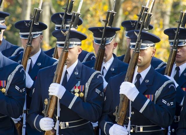 Soldiers in uniform march in formation, demonstrating precision and discipline at a ceremony.