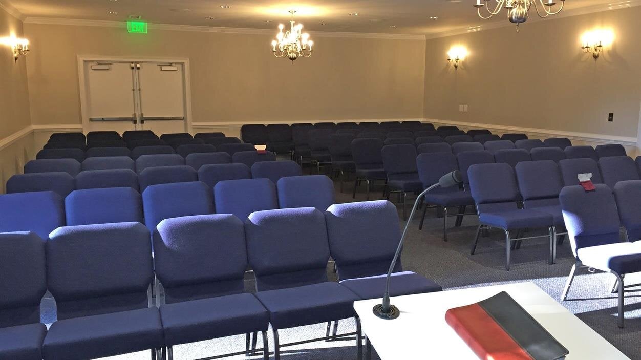 Chairs are arranged in a conference room with a table at the front, ready for a meeting.