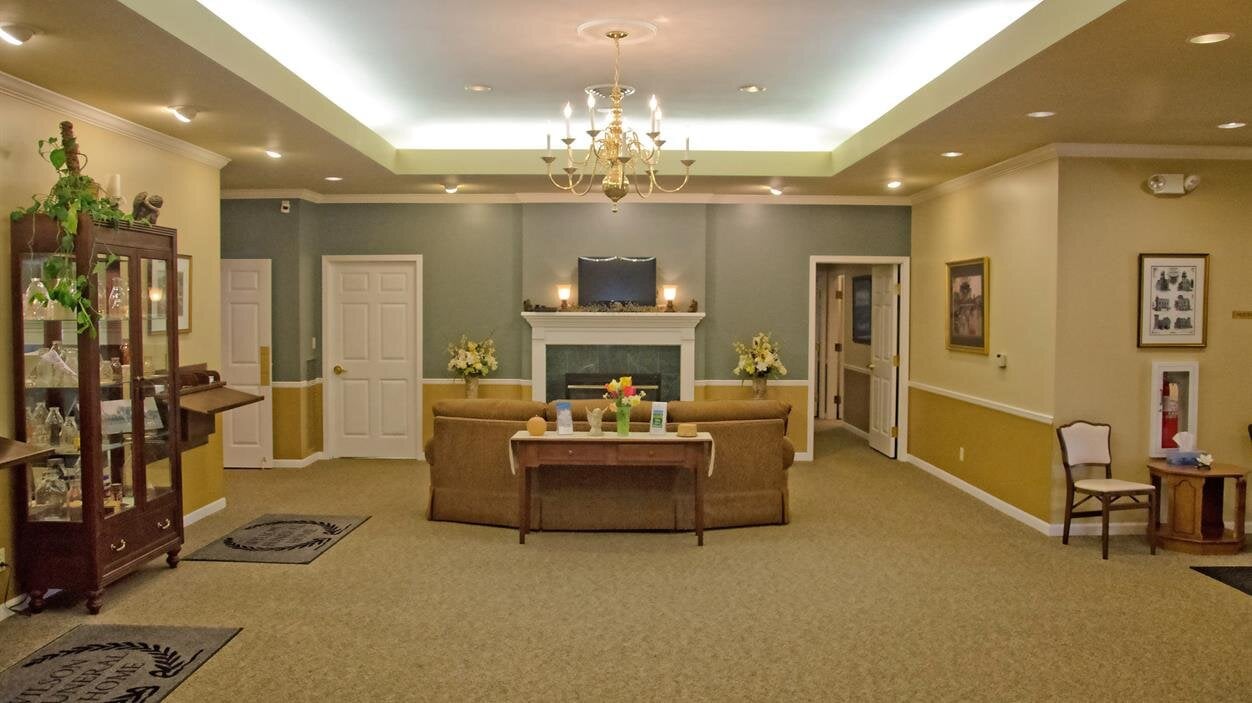 People walk through the reception area of a building with chairs and decorations.