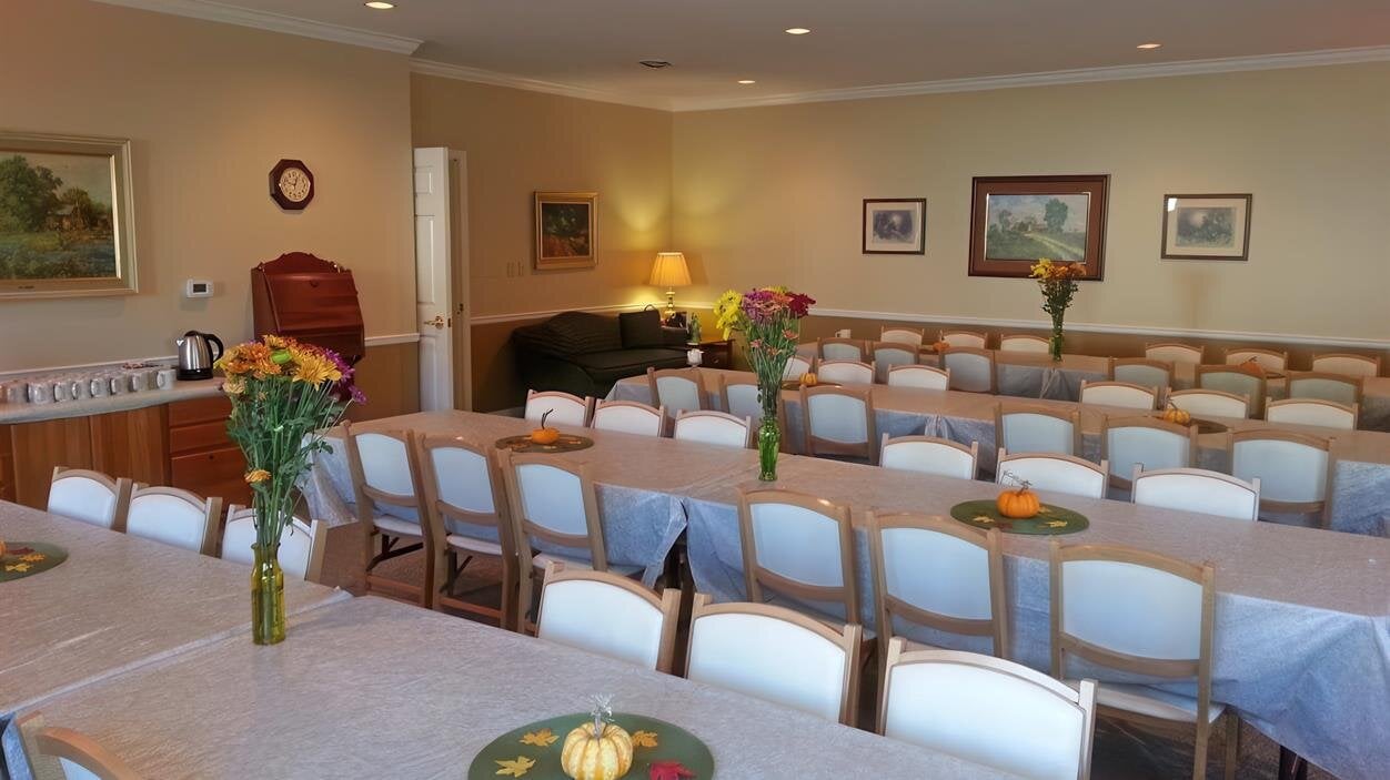 People are preparing a meeting room with tables set and decor in the background for an event.