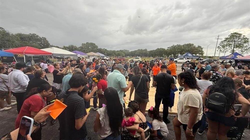 Many people crowd around a central area filled with activities during a spirited outdoor event.