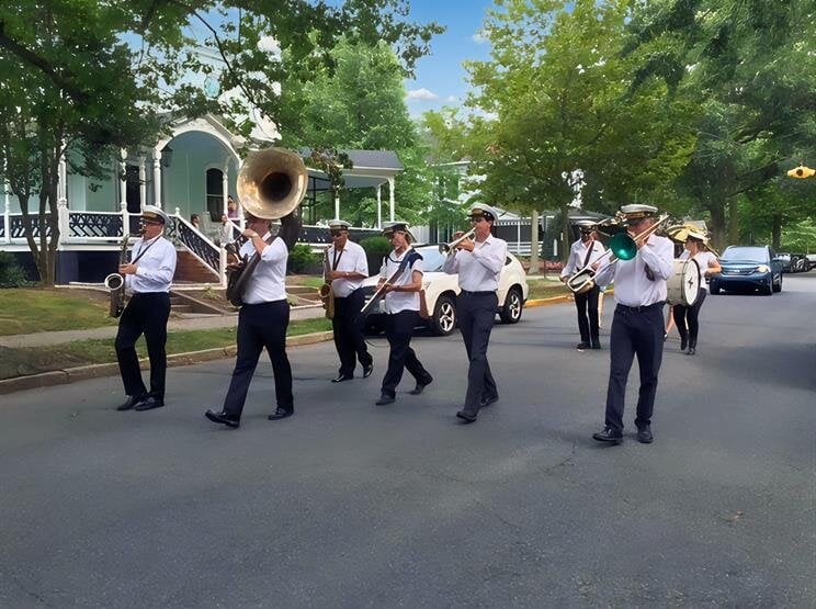 A group of musicians walks together on a street while playing instruments in the sun.