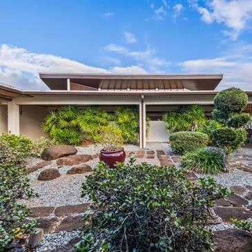 A serene garden house showcases modern design and lush greenery under a bright sky.