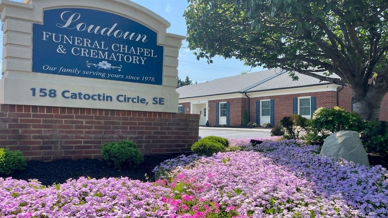 A sign with flowers in front of a building