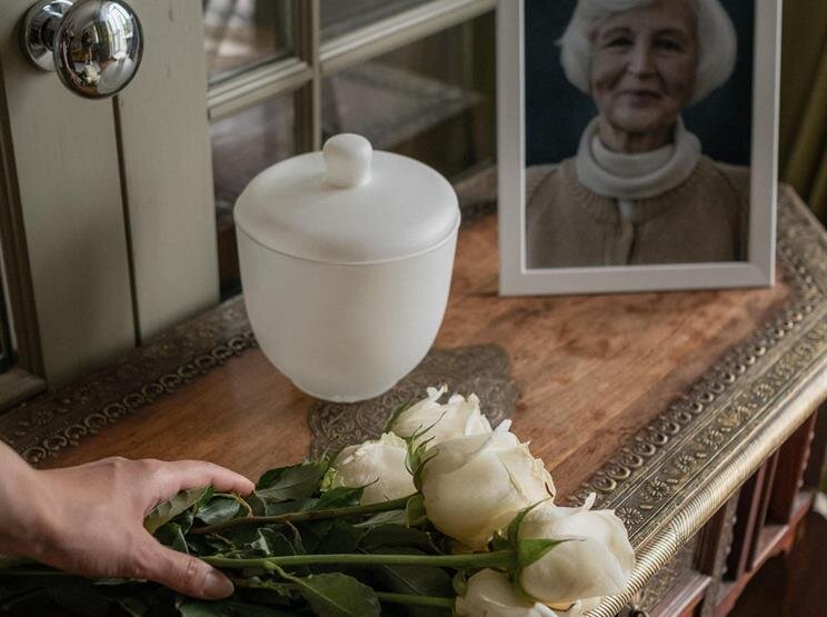 A hand holding a bouquet of white roses next to a picture of a woman