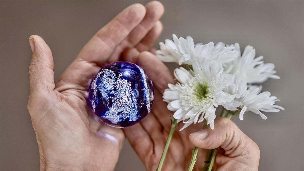 A person holding a glass globe and flowers