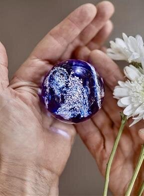 A person holding a glass globe and flowers