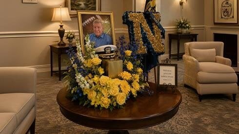 A room with a table with flowers and a picture of a man on it