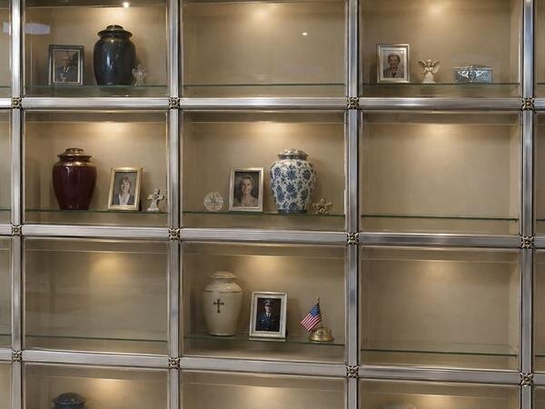 A glass display case with urns and pictures on it