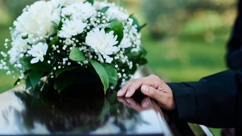 A person's hand touching a bouquet of flowers