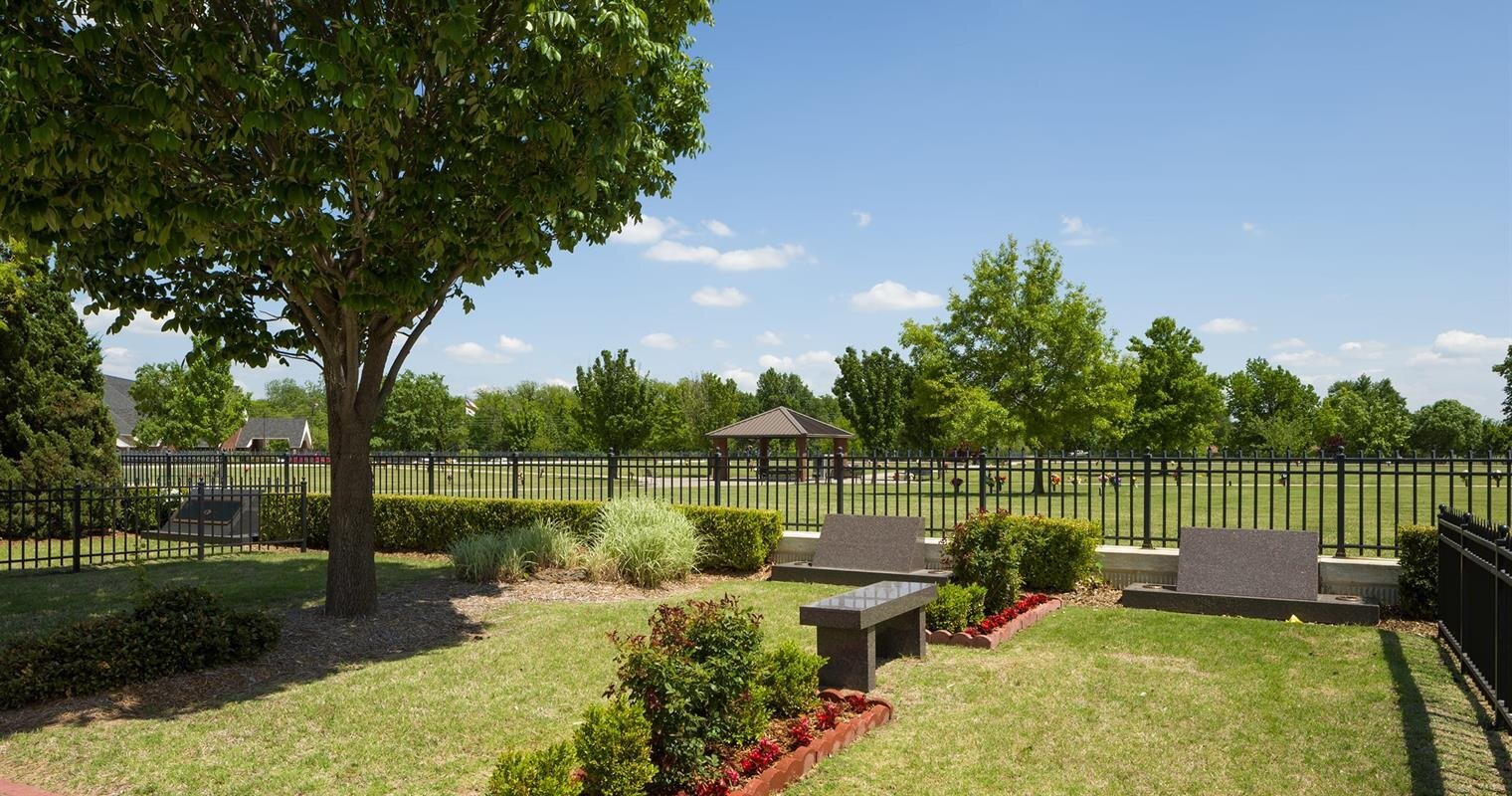 Bright sunny afternoon in a park with lush trees, vibrant flower beds, and a tranquil atmosphere.
