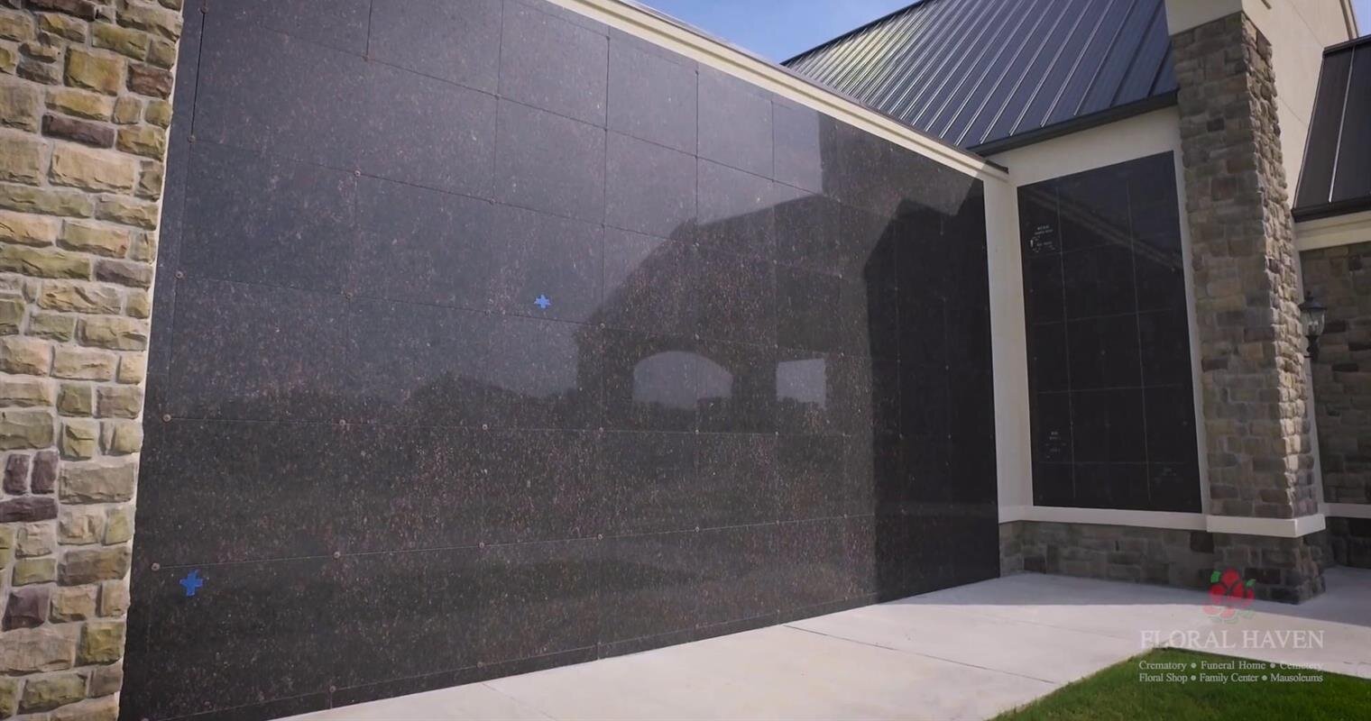 Dark stone cladding highlights a contemporary building design under sunlight and clear sky.