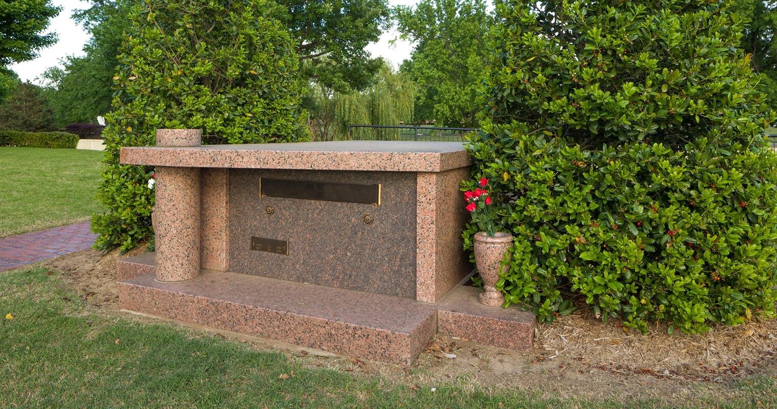 A tranquil memorial stands amidst verdant trees, offering a peaceful resting place in the park.