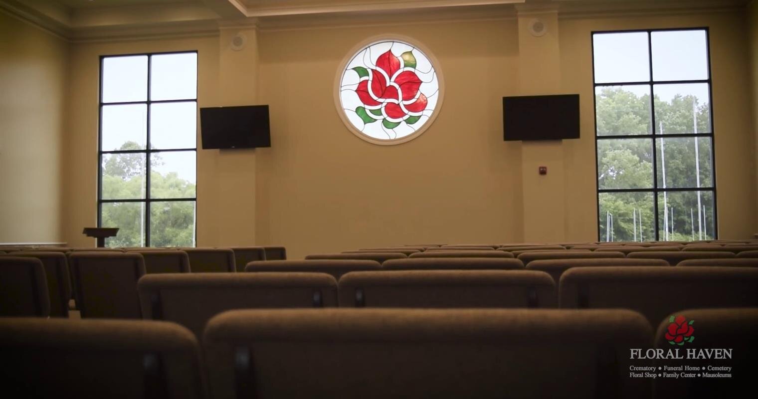 Bright chapel interior showcases comfortable seating and a beautiful stained glass window design.