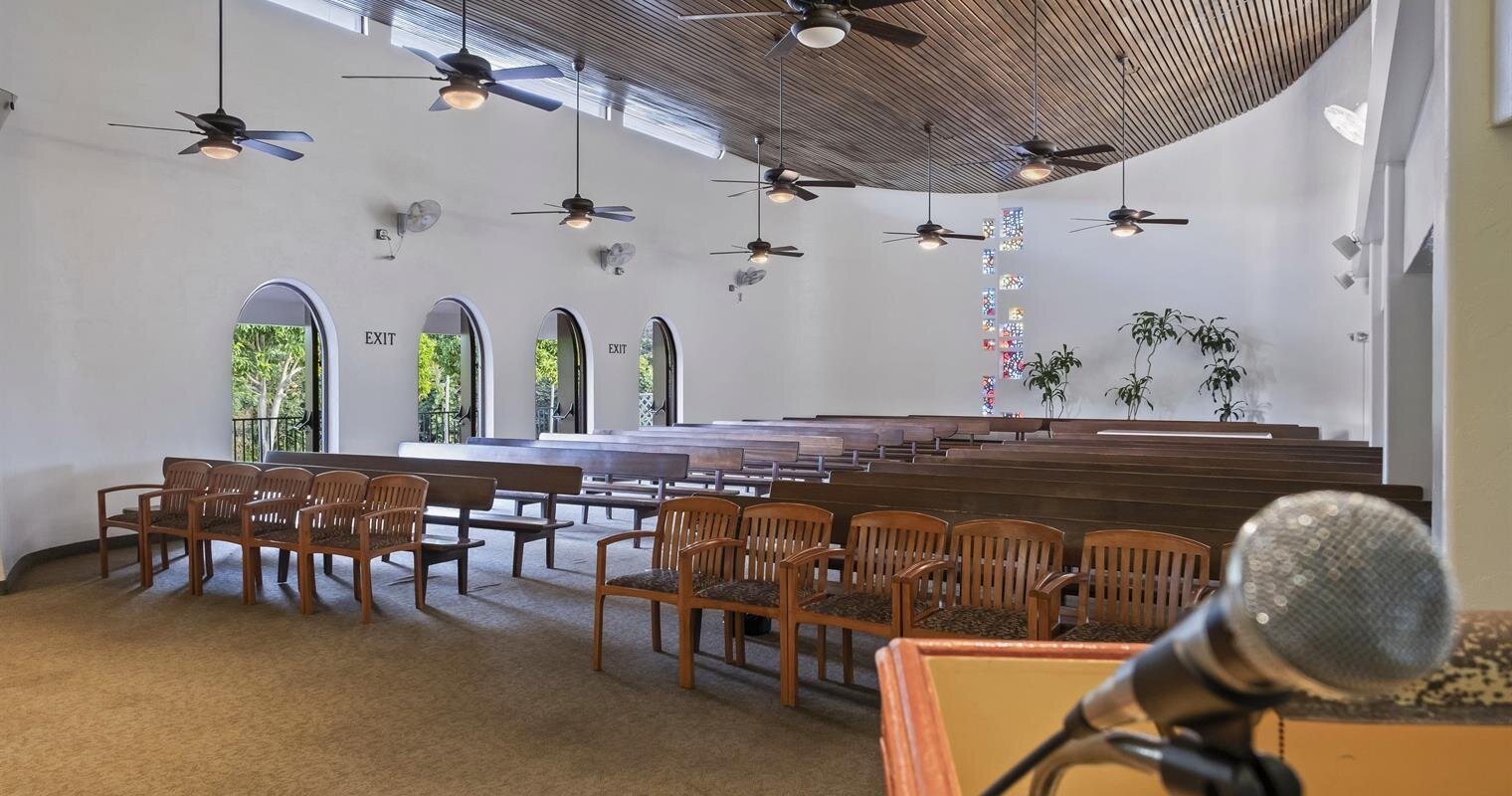 A modern hall with a curved wooden ceiling and rows of empty chairs ready for an event.