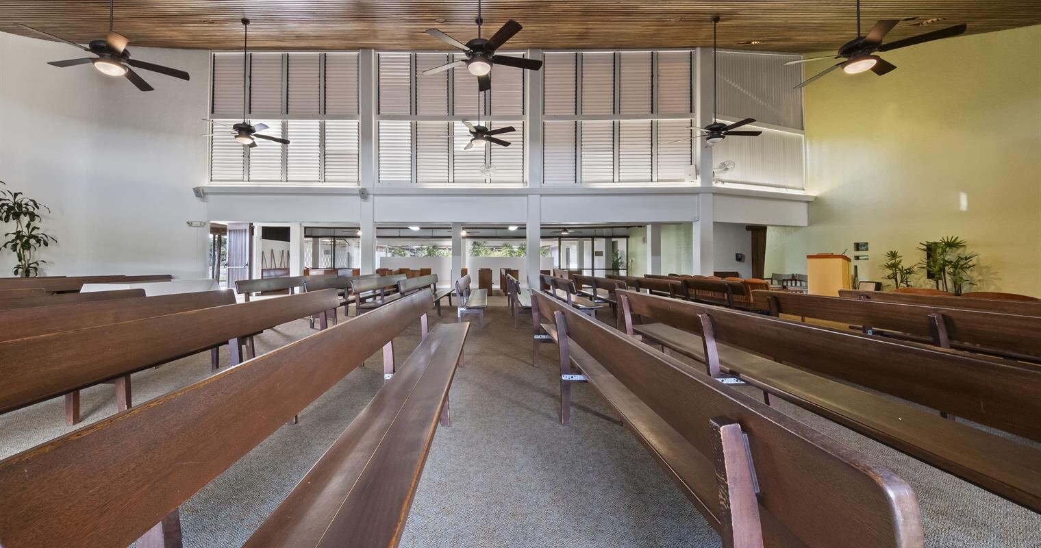 Benches are neatly lined up in a spacious hall with natural light and ceiling fans.