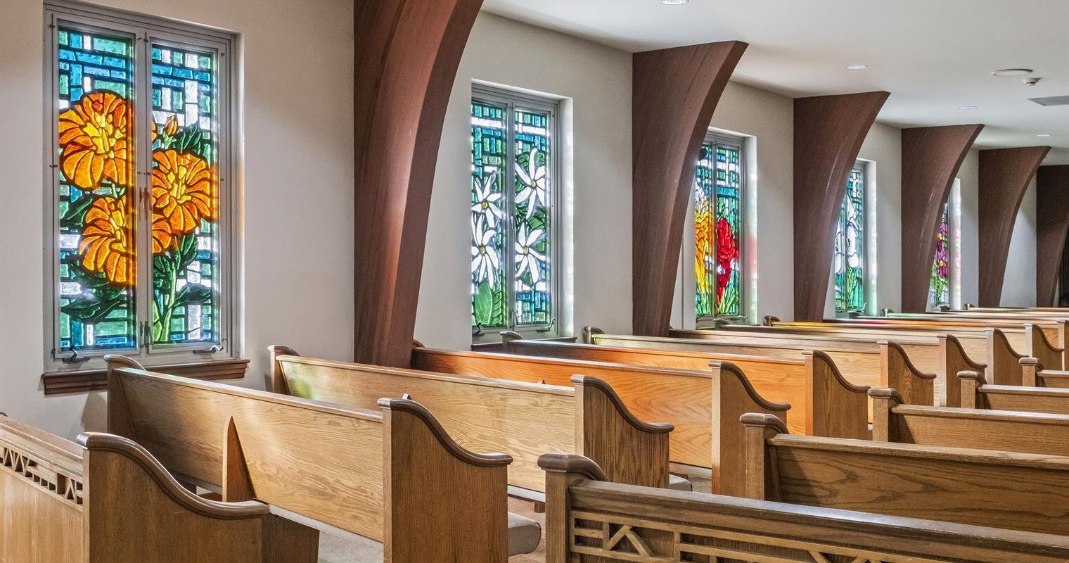 Colorful stained glass windows adorn a serene church, illuminating the wooden pews with light.