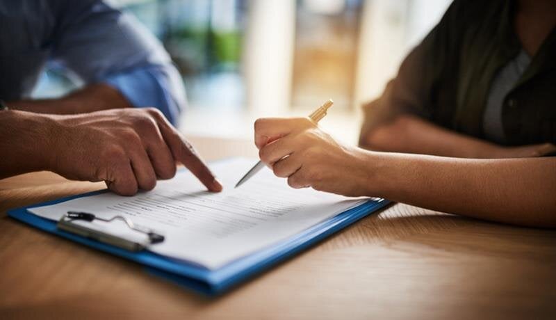 Two individuals engage in a detailed discussion over important documents at a table.