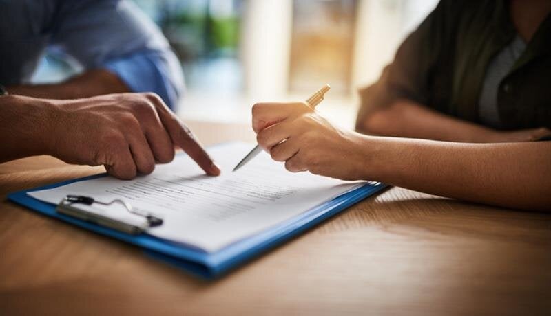 Two individuals engage in a detailed discussion over important documents at a table.