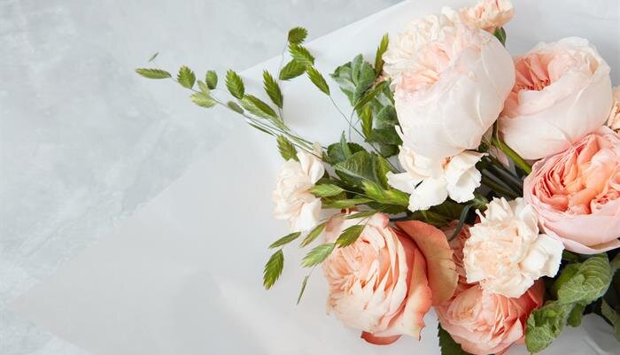 A delicate bouquet features pink and white roses interspersed with greenery, elegantly displayed.