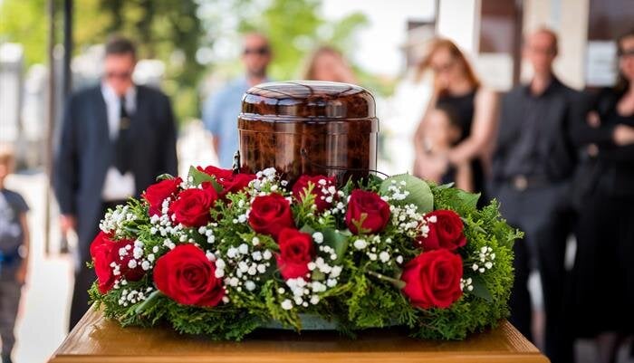Guests gather around a beautifully arranged urn with vibrant roses, honoring a loved one's memory.