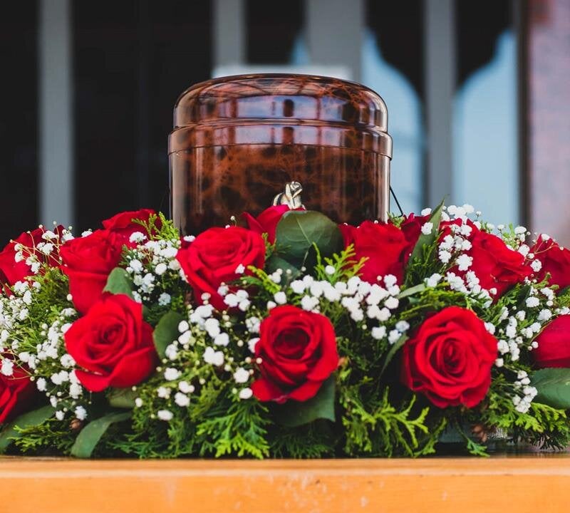 A beautiful display of red roses and an urn honoring someone's memory at a memorial.