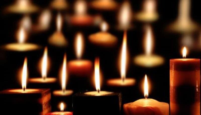 Flickering candle flames create a calming ambiance in a dimly lit space during an evening event.