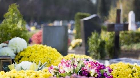 Visitors place vibrant flowers on graves in a serene cemetery, honoring loved ones during spring.