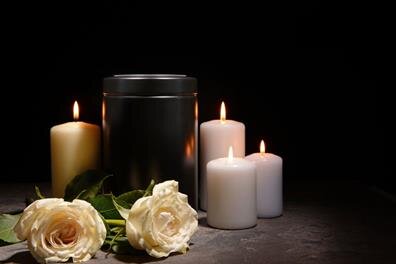 Candles and white roses are arranged on a table for a gathering in a dark room.