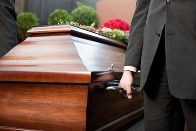 People are attending a funeral service. A casket is present as family and friends gather.