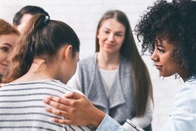 Women in a circle are sharing their thoughts and feelings while sitting in a room together.