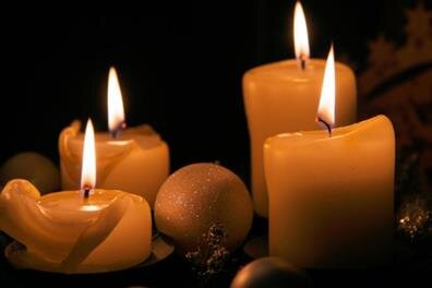 Five candles light up a dark space as their flames flicker quietly, creating warmth.