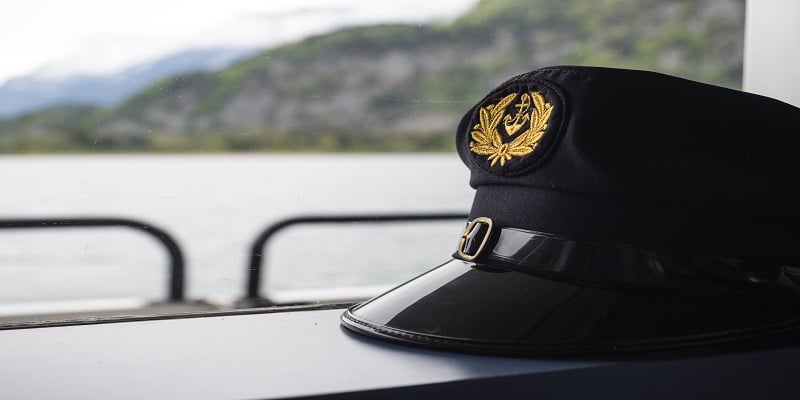 Navy captain’s hat resting by a window overlooking water and mountains, symbolizing military service and remembrance