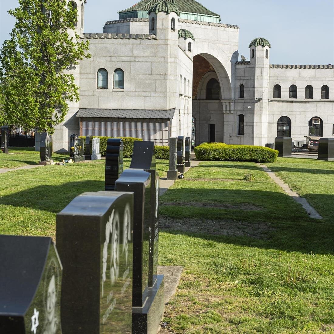 A cemetery with a building and a green lawn