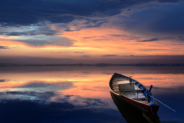 Small wooden boat resting on calm water at sunset, reflecting quiet remembrance in Albany memorial services