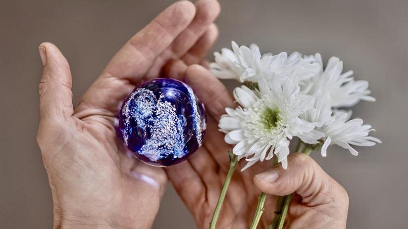 A person holding a glass globe and flowers