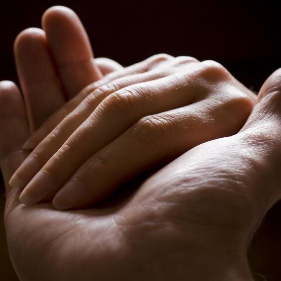 Two hands intertwine, symbolizing warmth and connection in a cozy indoor setting, evoking emotion.