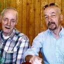 Two men engaged in conversation, laughing and enjoying each other's company indoors.
