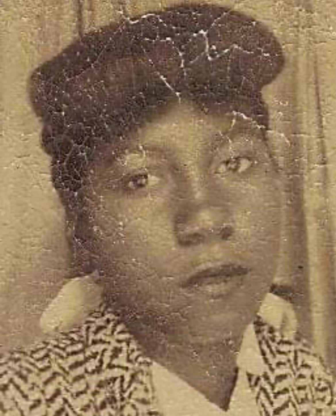 Young woman poses with confidence, wearing a hat and patterned jacket, captured in vintage style.