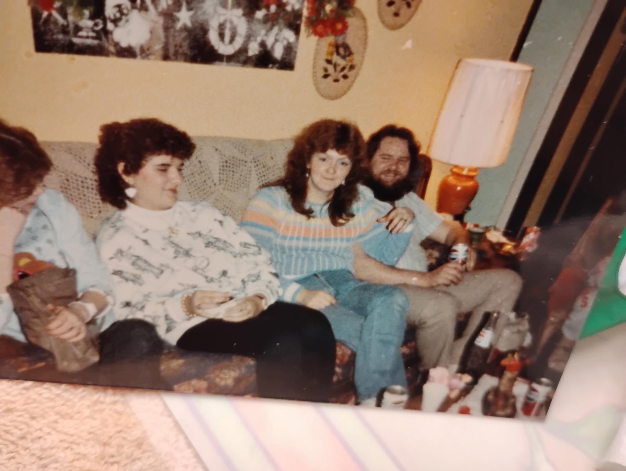 Group of friends relax together on a couch, enjoying drinks and conversation in a homey living room.