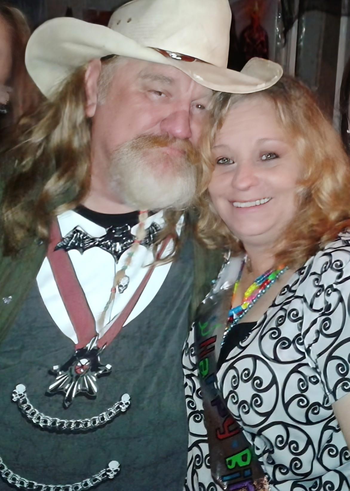 A couple smiles warmly while dressed in festive attire during a celebration filled with joy.