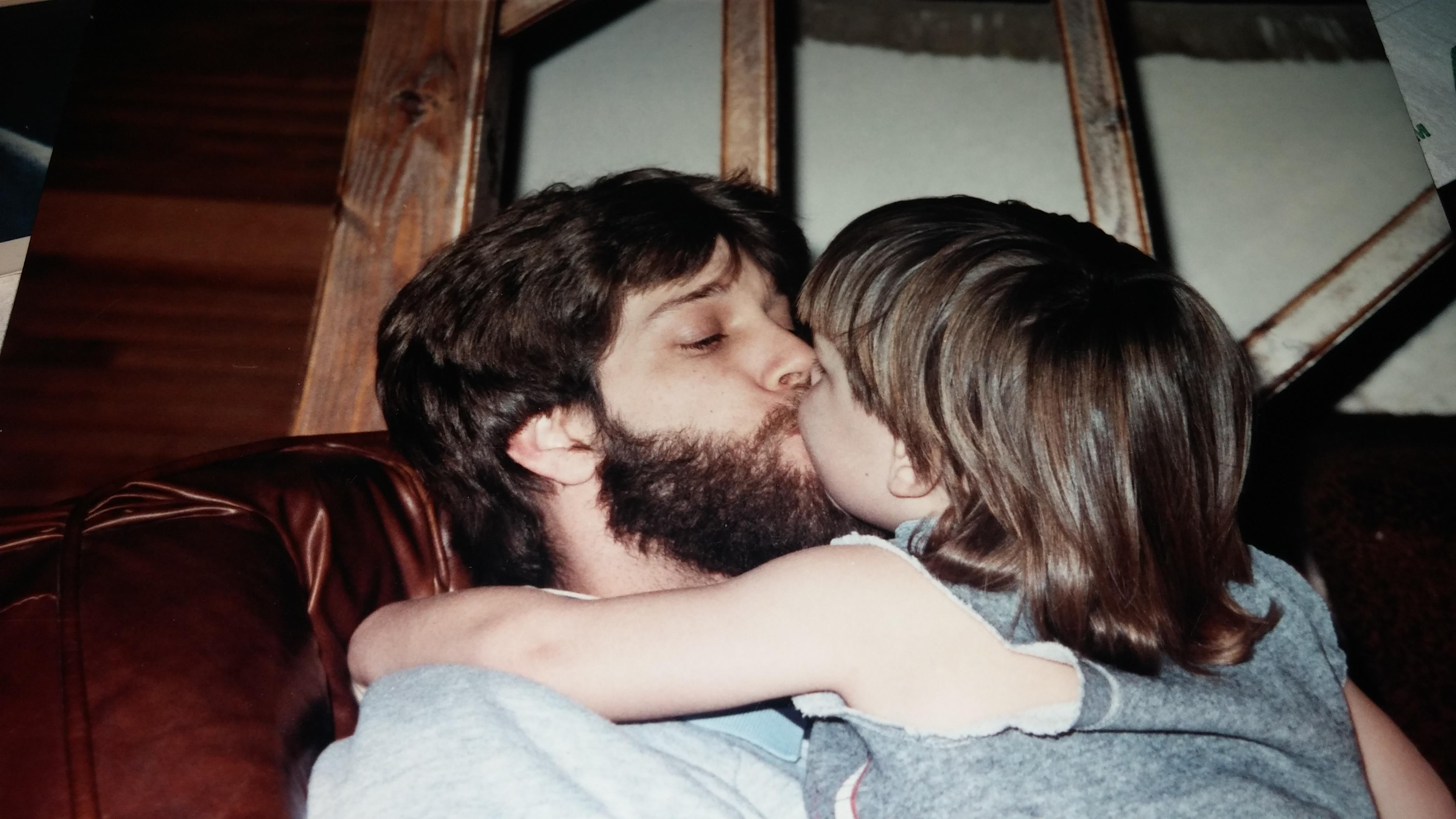 A loving father shares a tender moment with his child, enjoying an evening on the couch.