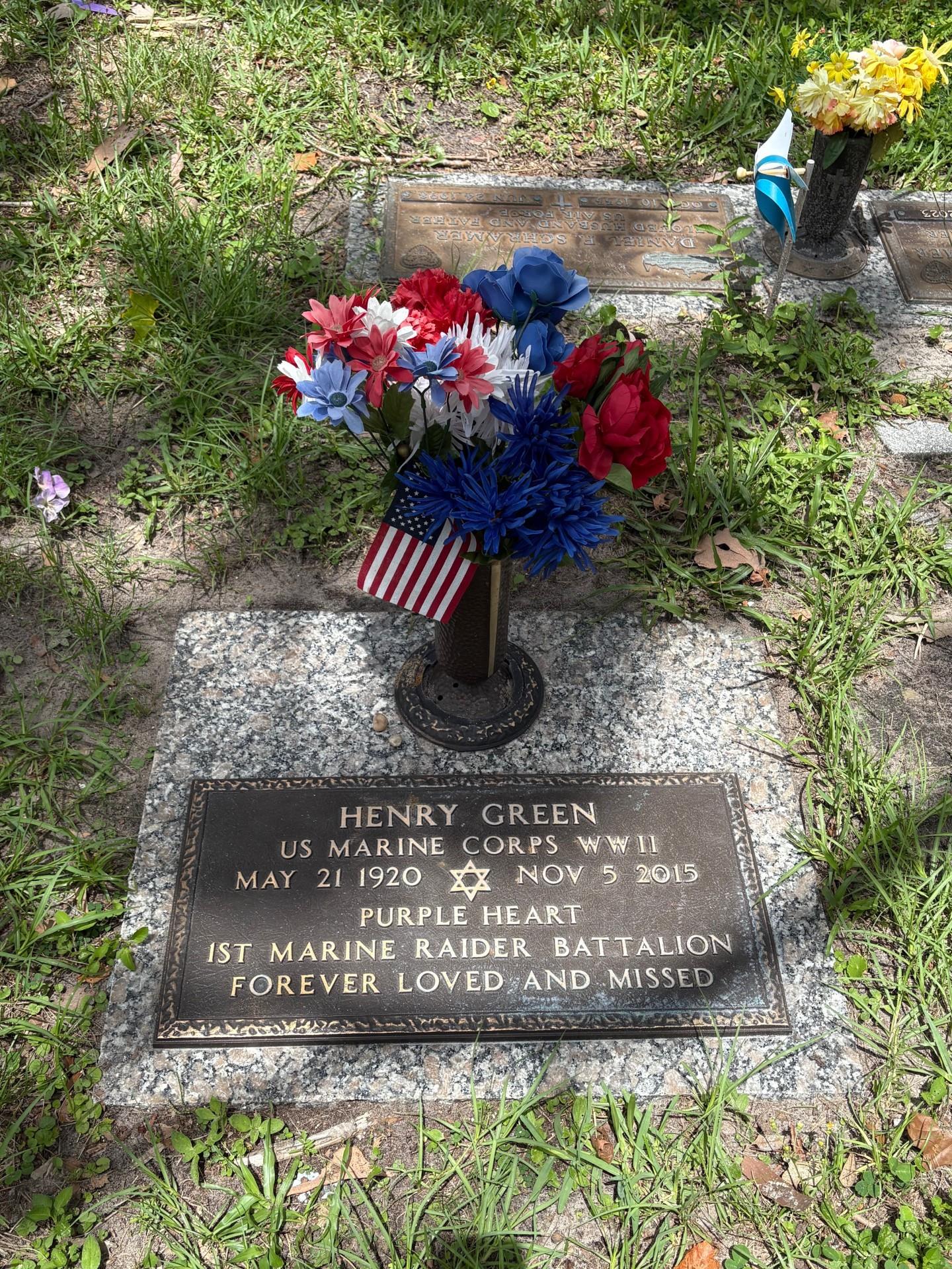 Gravesite of Henry Green features flowers and a flag, honoring his service in WWII and Purple Heart.