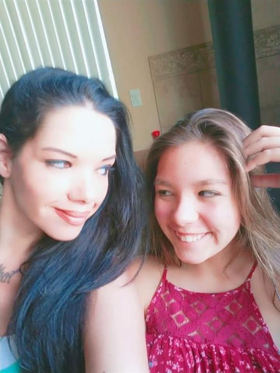 Two friends share smiles and laughter while sitting together in a bright indoor area.